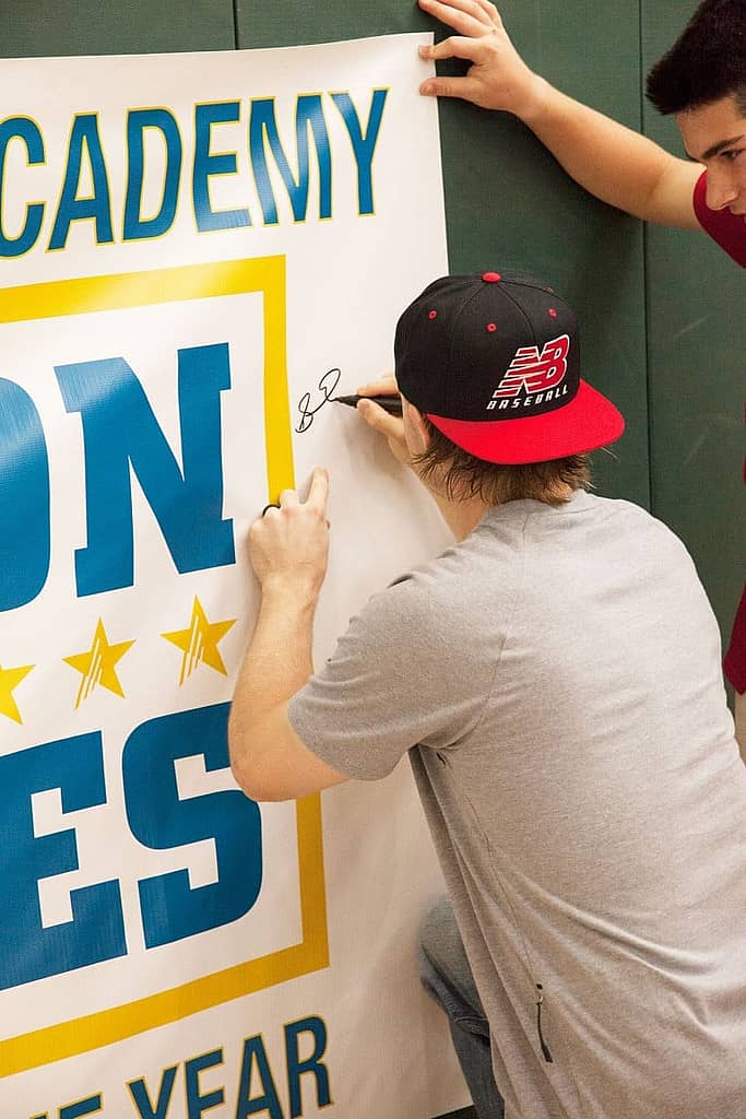 Brock Holt autographing a banner as a another man stands behind him