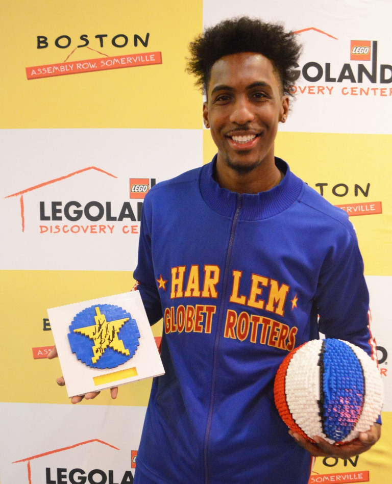 A Globetrotter posing for a picture holding a lego basketball and signed star plaque