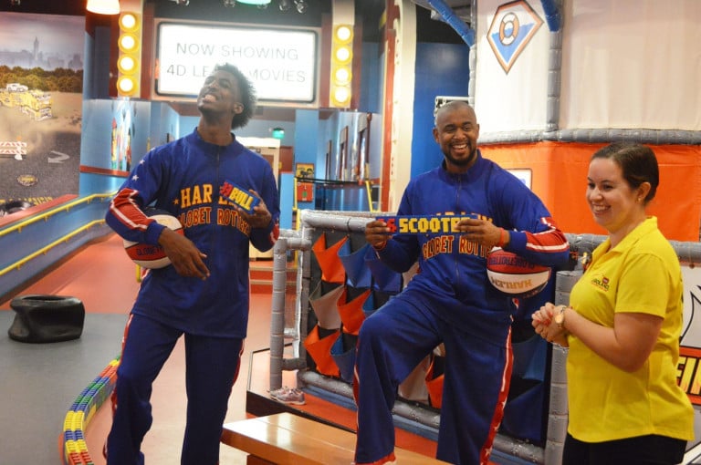 Two Globetrotter holding lego name plates and basketballs standing next to a woman
