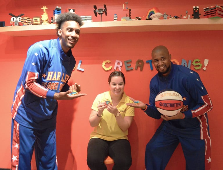 Two Harlem Globetrotters, one of whom is holding a basketball, posing with a woman