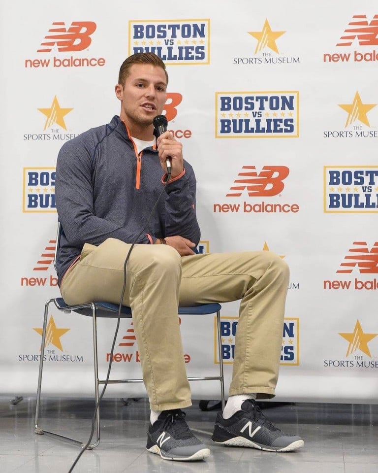 Justin Turri seated and holding a microphone in front of a promotional wall