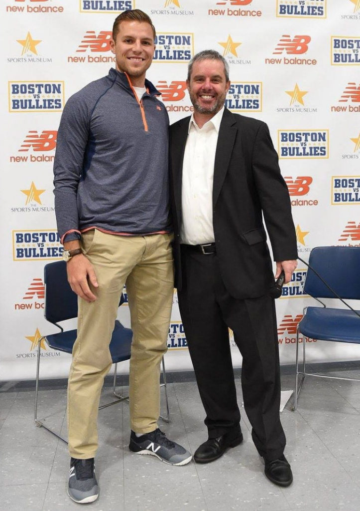 Justin Turri and another man posing for a picture in front of a promotional wall