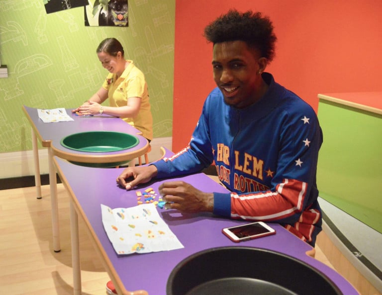 A Harlem Globetrotter and a woman seated at a table playing with legos