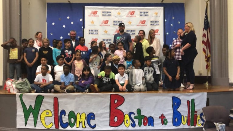 Brian Johnson standing on stage with a group of children above a "Welcome Boston to Bullies" banner