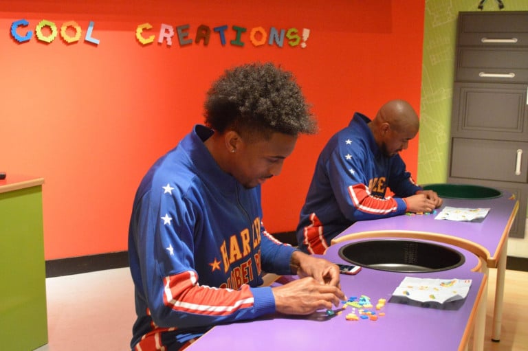 Two Harlem Globetrotters seated at a table playing with legos