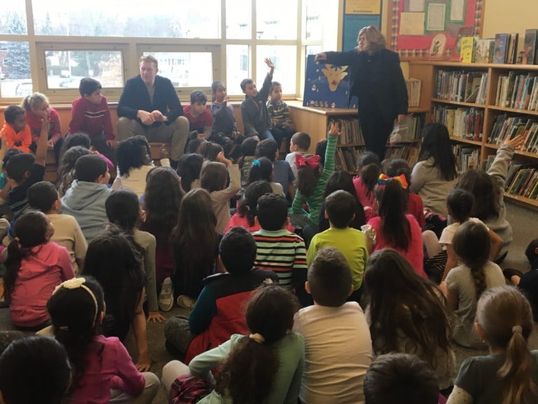 Brian Scalabrine seated talking to a group of children in a library, one of the children is raising his hand