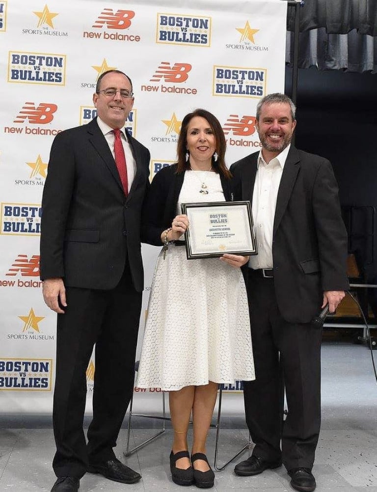 A woman holding a Boston vs. Bullies plaque flanked by two other men