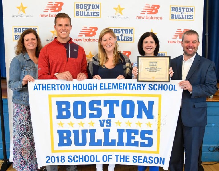 Justin Turri standing with three women and another man holding a Boston vs. Bullies banner and a small plaque