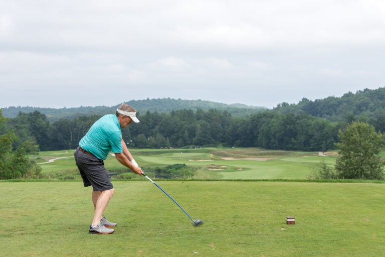 A man bends his knees and gets into position before a golf swing.
