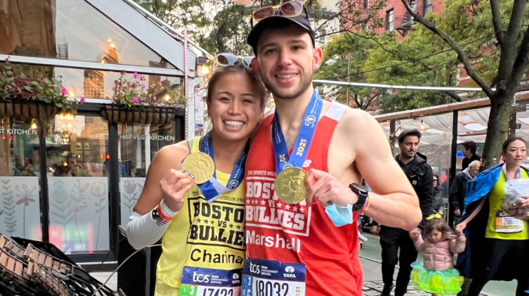 Two runners holding up their marathon medals